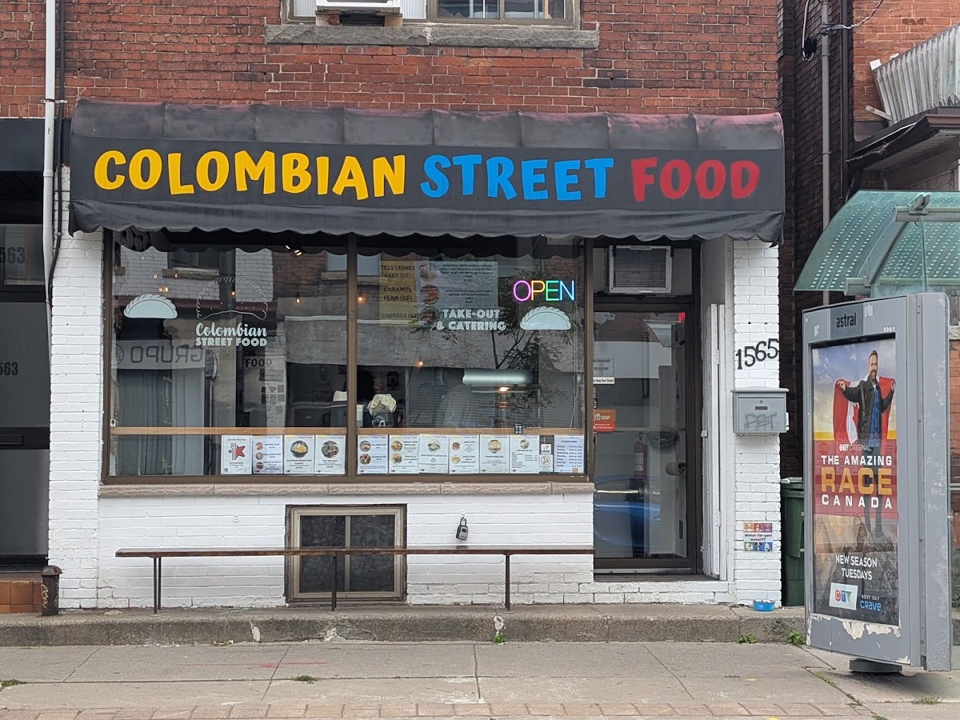 Colombian street food restaurant with a colorful awning on a brick building.