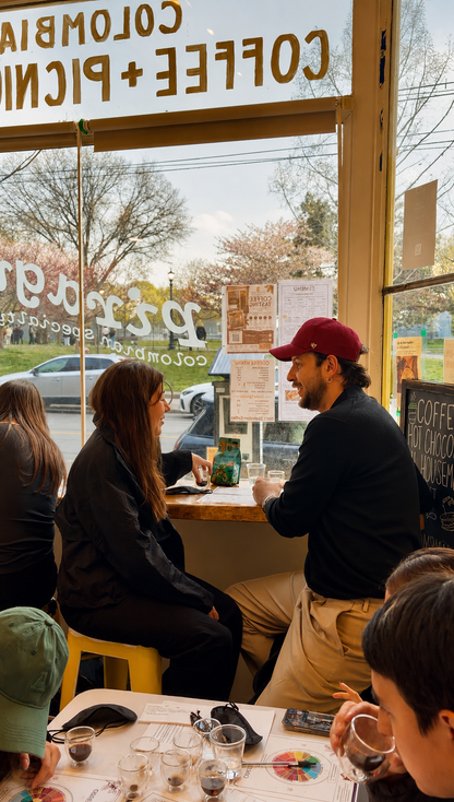 People sitting at a table inside a coffee shop with a view of the street outside.